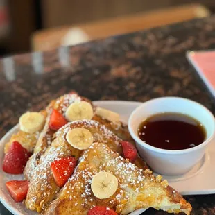 a plate of french toast with strawberries and bananas