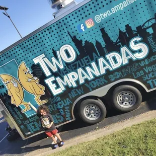 a young boy standing in front of a two empanadas truck