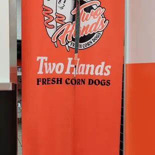a sign for two hands fresh corn dogs