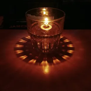a lit candle in a glass on a table