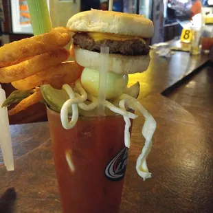 a bloody drink with a hamburger and onion rings