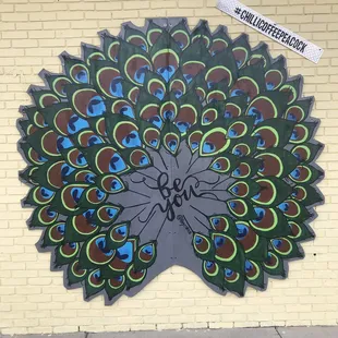 a colorful peacock on a brick wall