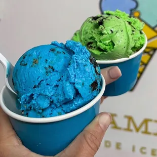 a hand holding two cups of ice cream