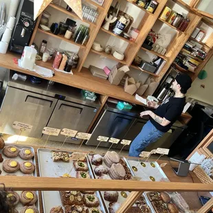 a woman standing in front of a display of pastries