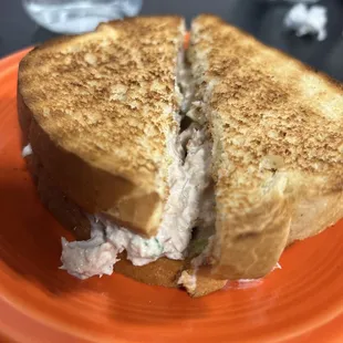 a sandwich cut in half on an orange plate