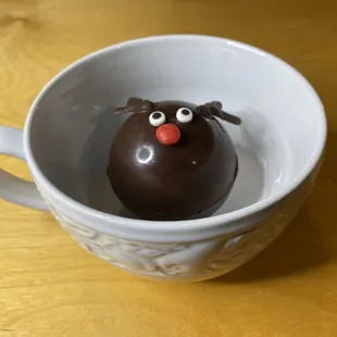 A different view of little Reindeer cocoa bomb tentatively resting in a huge mug.