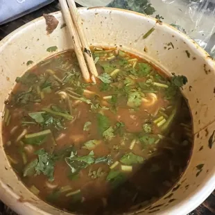 a bowl of soup with chopsticks