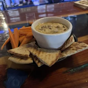Roasted garlic hummus served warmed with pita chips and carrots