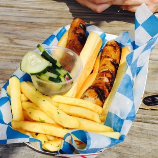 Two sausages with bread, pickles, and garlic fries