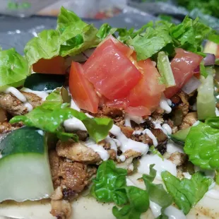 Chicken pita topped with tahini sauce lettuce and mixed vegetables