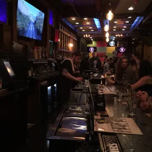 people sitting at a bar watching televisions