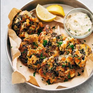 a plate of crab cakes with a side of dip