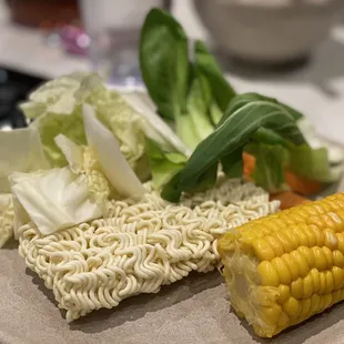 a plate of ramen noodles, corn and lettuce