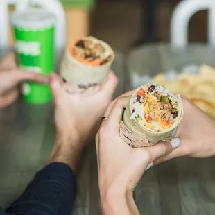 two people eating burritos at a table