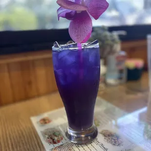 a purple flower in a tall glass