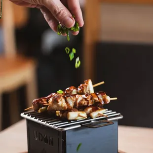 a hand sprinkling some food on a grill