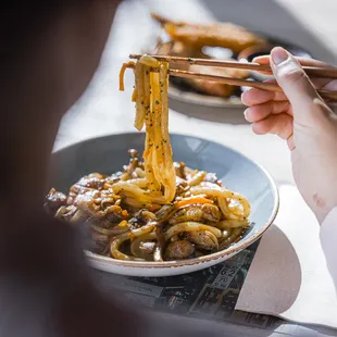 a person eating noodles with chopsticks