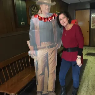 a woman standing next to a statue of a cowboy