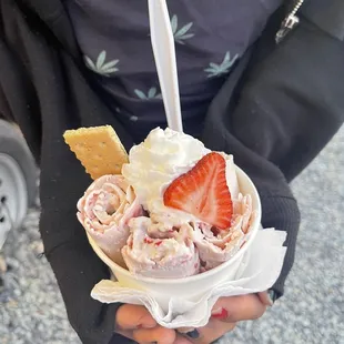 a person holding a bowl of ice cream and strawberries