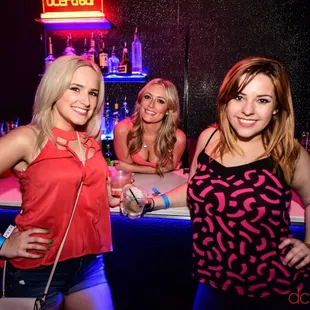 three women posing for a picture in front of a bar