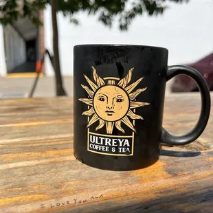 Ultreya mug on a picnic table that has &quot;I love you ^_^&quot; written in black ink.