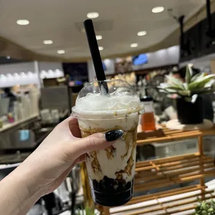 a hand holding a cup of iced coffee