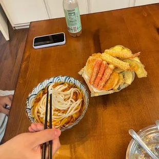  a person holding chopsticks over a bowl of ramen