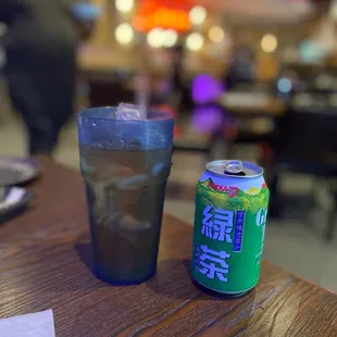 a glass of water and a can of soda on a table