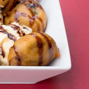 Deep fried oreos topped with chocolate drizzle and a side of vanilla ice cream