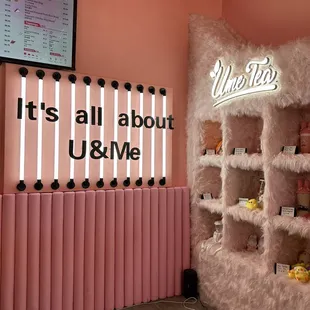 a pink wall with a neon sign that says it's all about u &amp; me