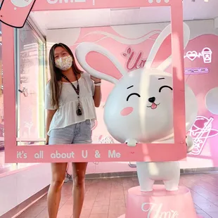 a woman standing in front of a pink bunny statue