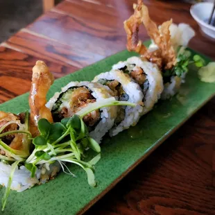 a sushi roll with shrimp and vegetables on a green plate