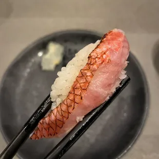 chopsticks holding a piece of sushi