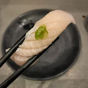 chopsticks holding a piece of sushi