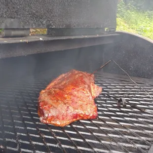 Brisket cooking in the smoker. Caught a shot, don&apos;t tell.