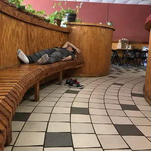 a man sleeping on a wooden bench