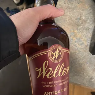 a hand holding a bottle of weller