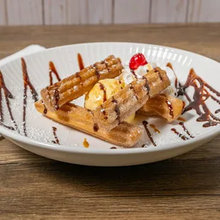 a plate of waffles with ice cream and syrup