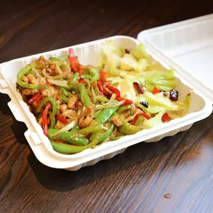 a styrofoam takeout container filled with stir fried vegetables