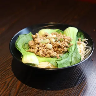 a bowl of noodles with meat and lettuce