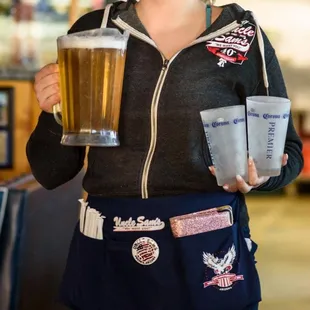 a woman holding two cups of beer