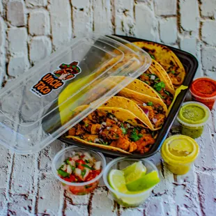 a tray of tacos and salsa