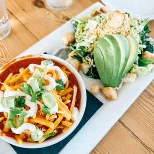 a bowl of chili and a salad on a plate
