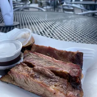 a plate of ribs and sauce on a table