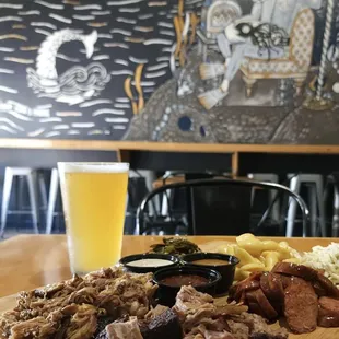 a plate of meat, potatoes, and a glass of beer