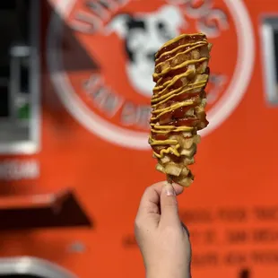 a hand holding a waffle cone in front of a food truck