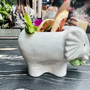 a white elephant planter with sandwiches in it