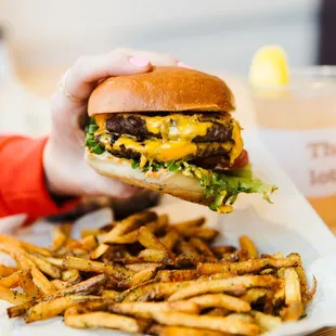 a person holding a cheeseburger and fries