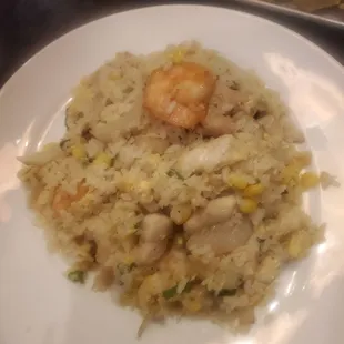 a plate of rice with shrimp and corn