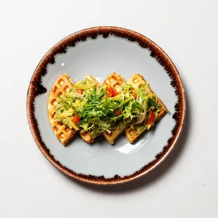 a plate of waffles with lettuce and tomatoes